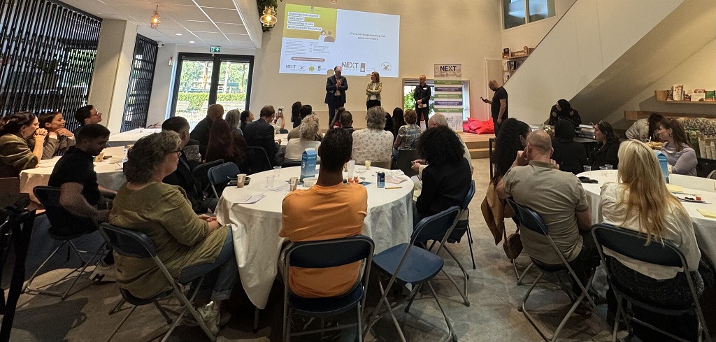 Mensen volgen een de presentatie van Dienst Toeslagen in een zaaltje.