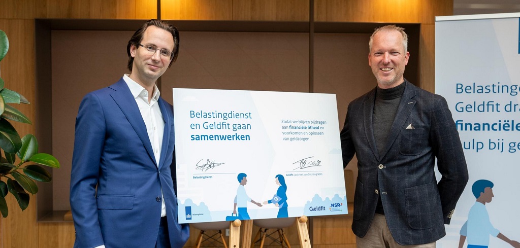 Julien Spliet (directeur-generaal Belastingdienst) en Martin Suithoff (algemeen directeur van de Nederlandse Schuldhulproute (NSR)) poseren naast het ondertekende convenant Geldfit.