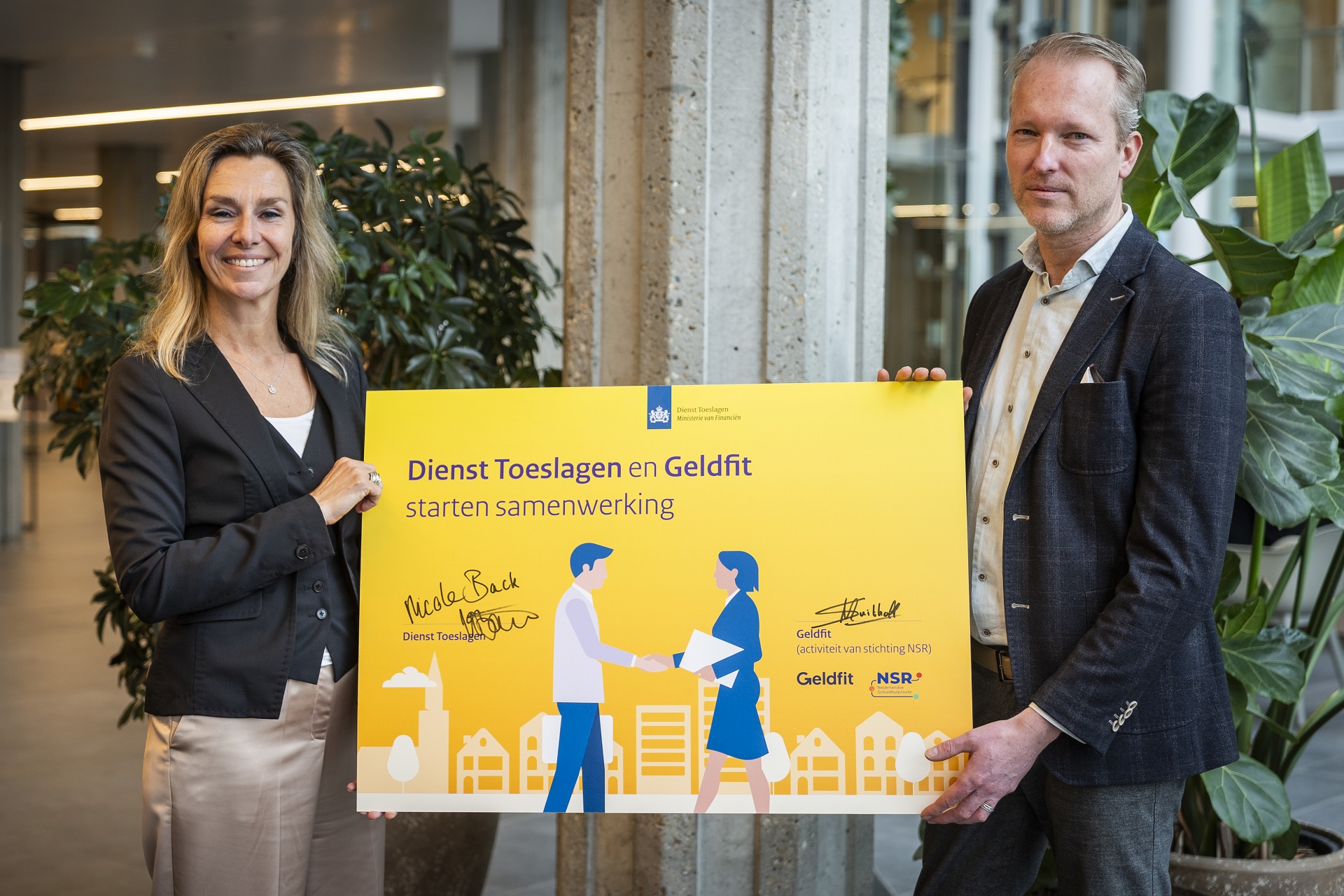 Algemeen directeur Nicole Back van Dienst Toeslagen met de ondertekende samenwerkingsovereenkomst met Geldfit.