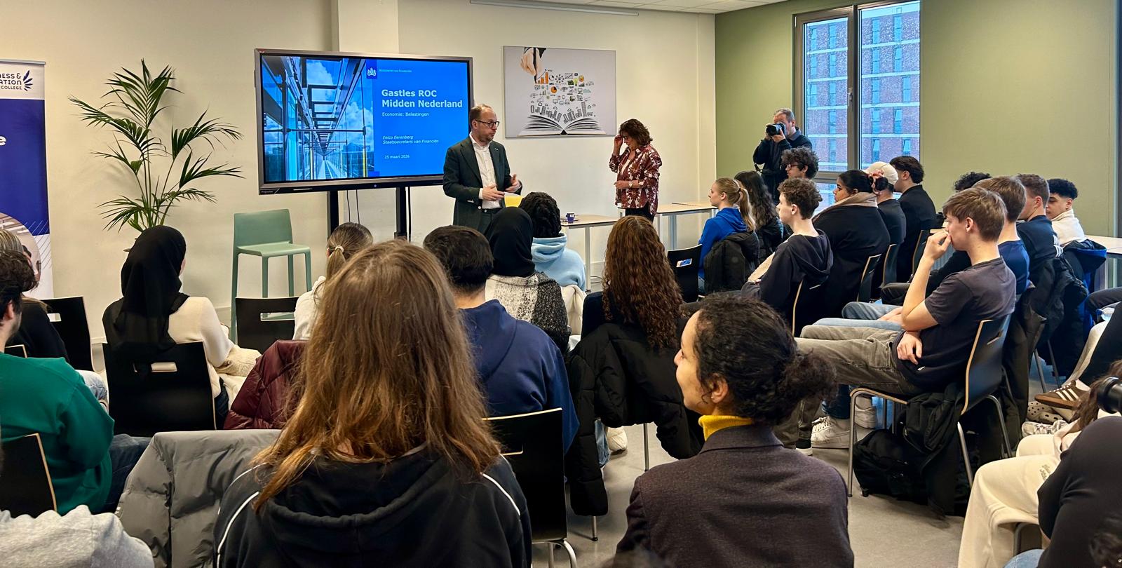 Staatssecretaris van Financiën Eelco Eerenberg staat voor een groep mbo-studenten en geeft gastles over belastingen.